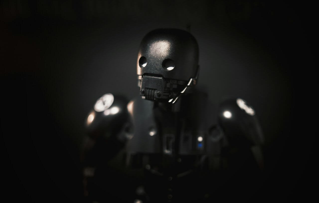 A spooky black robot toy dropping a shadow on a black wall